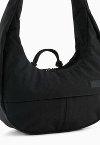 Czarna nylonowa torba na ramię o zaokrąglonym kształcie, teksturowanej powierzchni, elastycznym uchwycie i zamknięciu na zamek; charakteryzuje się eleganckim, minimalistycznym stylem.