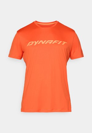 Krátky rukáv, oranžové športové tričko vyrobené z ľahkej látky s bielym nápisom "DYNAFIT" na hrudi. Hladká textúra.