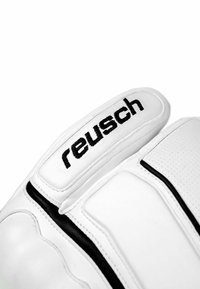 Weißer Torwarthandschuh mit strukturiertem Oberflächen, schwarzen Akzenten und gesticktem "reusch"-Logo am Riemen. Aus glattem Leder.
