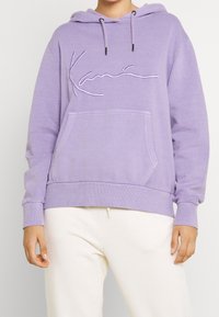 Lila hoodie med kängurufickor, med broderad text på framsidan. Mjuk, texturerad tyg; ribbad ärm och nederkant.