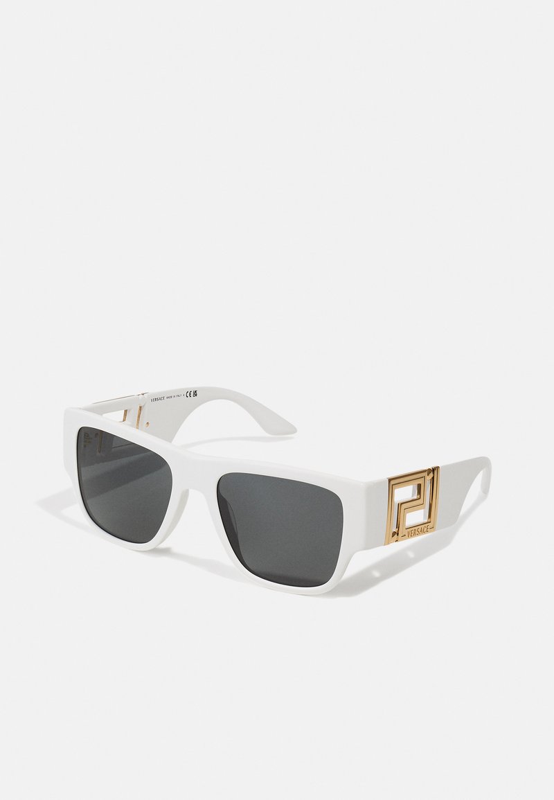 Lunettes de soleil carrées blanches avec verres gris, présentant des détails en métal doré et un logo discret sur le côté. Fini mat et design robuste.