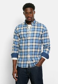 Blau-weiße karierte Button-Up-Hemd mit kontrastierenden marineblauen Manschetten, die über eine Baumwollmischung und ein klassisches Kragen-Design verfügt.