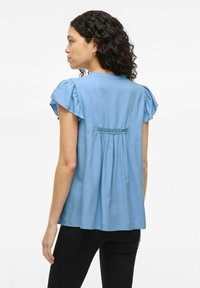 Light blue short-sleeve blouse with gathered detailing on sleeves and back, featuring delicate lace accent above a pleated design.