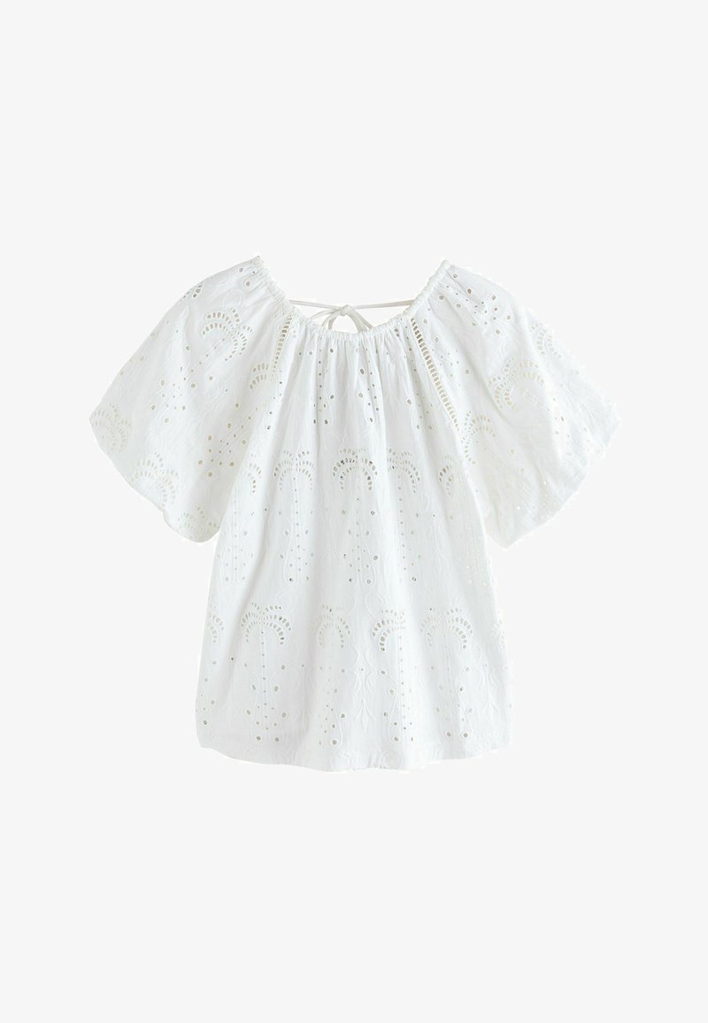 Blouse en coton blanc avec broderie ajourée, larges manches courtes, encolure froncée et un petit lien à l'arrière.