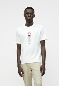 Biela bavlnená tričko s farebnou grafikou lebky s plameňmi nad ružovým zapaľovačom. Krátke rukávy a dizajn s okrúhlym výstrihom.