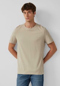 Beige katoenen t-shirt met een ronde hals en korte mouwen, met een subtiel merkembleem geborduurd op de borst.