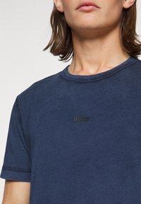 Ναυτικού μπλε βαμβακερό t-shirt με κοντά μανίκια, διαθέτει στρογγυλή λαιμόκοψη και μια διακριτική μαύρη λογότυπο "BOSS" στο στήθος. Λείος υφή.