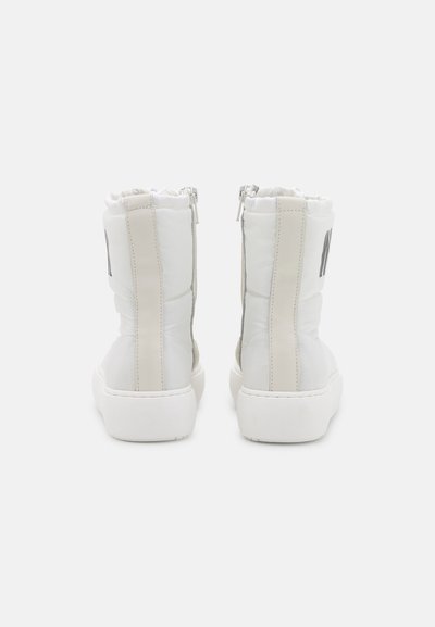 Botas brancas até ao tornozelo com acabamento brilhante, fecho de zip na parte de trás, parte superior com almofada suave e detalhes em bege contrastantes ao longo dos lados.