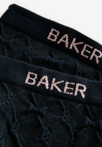 Calcetines negros con textura y un patrón de diamantes, con una cinturilla de punto que presenta la palabra "BAKER" en rosa. Tela suave, diseño sencillo.