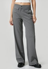 Grijze, gestreepte, wijde broek met een knoopsluiting en achterzakken. Gemaakt van een structuurstof, rustend boven op plateauschoenen.