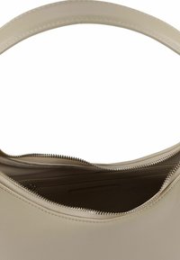 Borsa a tracolla in pelle beige con una cerniera argentata parzialmente aperta che mostra l'interno vuoto e un manico a tracolla arrotondato.