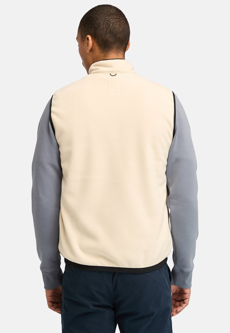 Gilet in pile di colore crema con maniche grigie, colletto alto e dettaglio posteriore. Tessuto testurizzato con accenti di colore a contrasto e rifiniture nere.