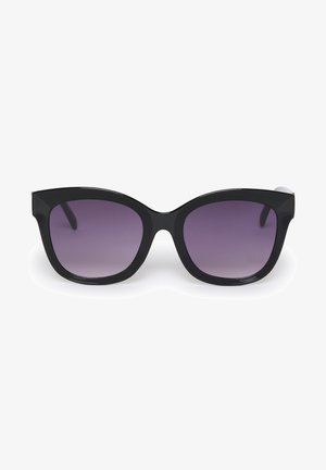 Ochelari de soare negri în stil cat-eye, cu lentile închise, ramă groasă din plastic și textură netedă, asortați cu un top negru cu maneci scurte, cu tente nervoase.