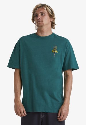 Teal cotton t-shirt with crew neck, short sleeves, and a small multicolored graphic design featuring abstract shapes on the chest.