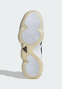 Semelle de chaussure présentant un design ondulé et texturé en blanc et beige avec des motifs circulaires ; inclut un accent du logo Adidas en noir.