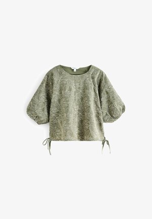 Light olive green top with a textured floral pattern, featuring puffed sleeves and drawstrings at the hem. Smooth fabric with a rounded neckline.
