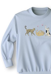 Lichtblauwe sweatshirt met drie geïllustreerde katten die spelen, met gedetailleerde afdrukken van verschillende kleuren en patronen op de katten.