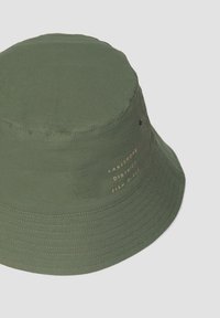 Grüner Bucket-Hut aus einem Stoff mit glatter Textur. Verfügt über bestickten Text an der Seite in Gold, mit einem runden, breiten Rand.