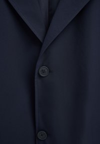 Marineblauer Blazer mit Kerbkragen und zwei sichtbaren schwarzen Knöpfen, jeder mit "Polo Club" Gravur.