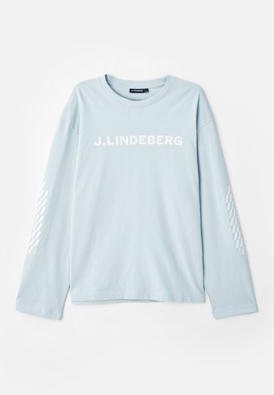 Hele sinine pika varrukaga T-särk pehme kangaga, mille esiosas on valge "J. Lindeberg" logo ja varrukatel on mustriga aksent.