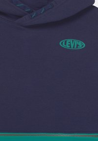 Felpa con cappuccio blu navy con accenti turchesi e logo Levi's verde. Dotata di cappuccio con coulisse e tasca frontale con zip. Tessuto morbido al tatto.