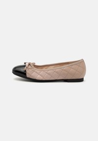 Punta in vernice nera, corpo in pelle beige trapuntata con dettaglio a fiocco. Design piatto con suola nera bassa.