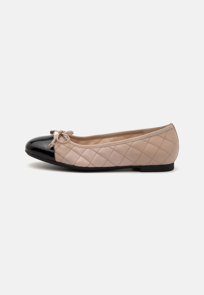 Bout à capuchon en cuir verni noir, corps en cuir beige matelassé avec un détail de nœud. Design plat avec une semelle noire basse.