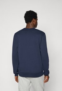 Mørkeblå sweatshirt med rund hals og lange ærmer, lavet af blødt stof. Har ribstrikkede manchetter og kant for ekstra struktur.