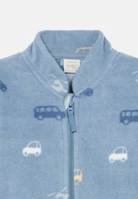 Ανοιχτό μπλε fleece μπουφάν με φερμουάρ. Διαθέτει σχέδια αυτοκινήτων σε σκούρο μπλε, λευκό και κίτρινο. Μαλακή υφή με ψηλό γιακά.