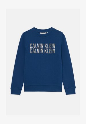 Sweatshirt azul feito de algodão, com decote redondo, punhos e bainha canelados. Na frente, exibe "CALVIN KLEIN" em impressão metálica.