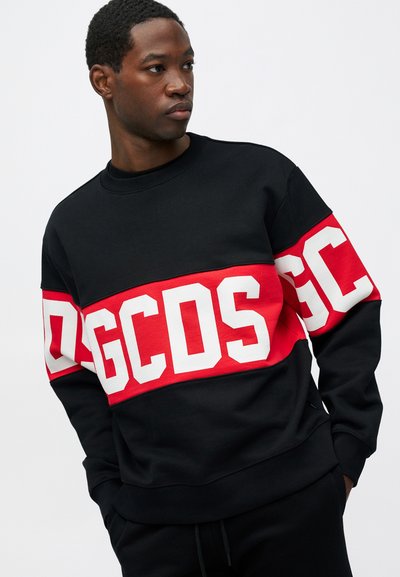 Μαύρο φόρεμα με κόκκινη λωρίδα που έχει μεγάλες λευκές λέξεις "GCSD". Ριμπ γιούρι και μανίκια, μαλακή υφή, casual σχεδίαση.