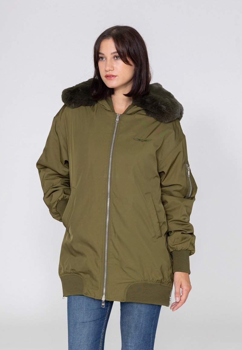 Olijfgroene bomberjack met een nepbont kraag, voorrits en geribde manchetten. Voorzien van zijzakken en een relaxte pasvorm.