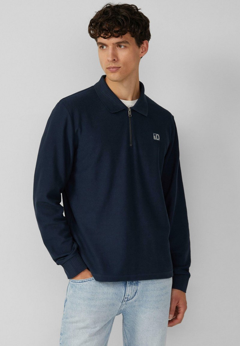 Navy Zip-Polohemd mit geripptem Kragen und Bündchen, versehen mit einem kleinen Logo auf der linken Brust und einem strukturierten Stoffdesign.
