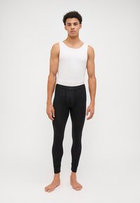 Black leggings made of stretchy material, featuring a snug fit, tapered cuffs, and a flat waistband, worn with a white tank top.