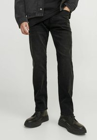Svarta denimjeans med rak skärning, med en urtvättad textur. Matchas med svarta, kraftiga snörskor.