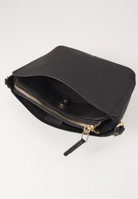 Zwarte leren handtas met een klepsluiting, gouden rits en verstelbare schouderband; interieur met een gladde voering en een drukknoop.