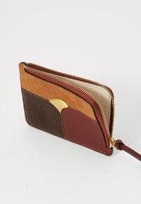 Portafoglio in pelle marrone e ruggine con un pannello strutturato marrone, un accento rosso liscio, hardware dorato e chiusura con cerniera.