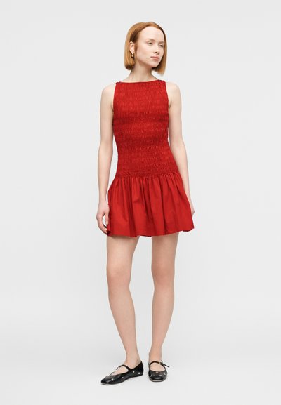 Κόκκινο αμάνικο φόρεμα με σμόκιν στην μπλούζα και φουσκωτή φούστα. Κατασκευασμένο από ελαφρύ ύφασμα. Φοριέται με μαύρα μπαλαρίνα παπούτσια. Ομαλή υφή.