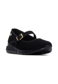 Zapato Mary Jane de ante negro con punta redonda, tira elástica y detalle de hebilla dorada sobre una suela negra texturizada.