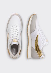 Baskets blanches et grises avec une surface en mesh texturé, des accents dorés à motif serpent, et une semelle en caoutchouc. Dotées d'un design à lacets et d'un logo.