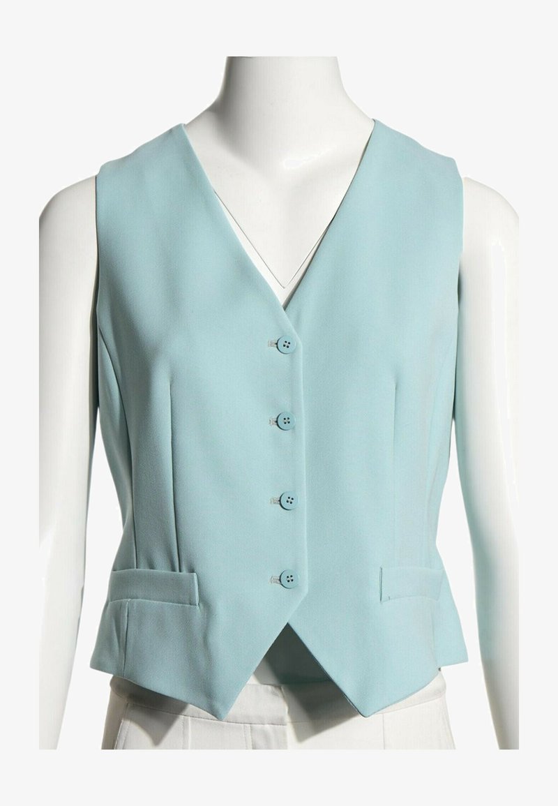 Veste sans manches bleu clair avec quatre boutons sur le devant et deux petites poches avant, portée sur un mannequin.