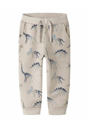 Beige børnesvedbukser med dinosaur-skeletmønstre i blå og grå nuancer, udstyret med elastisk talje og snøre.