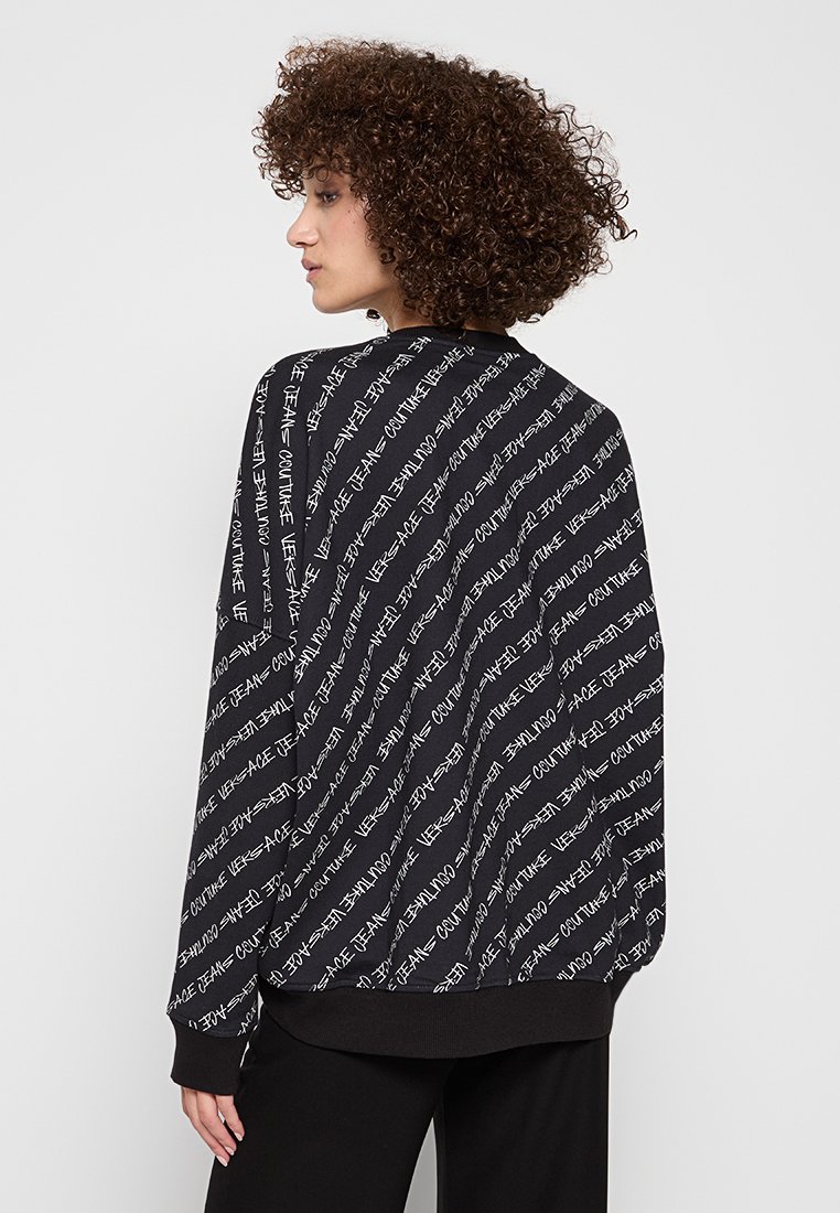 Sudadera negra con patrón de texto blanco, con un corte relajado y dobladillo acanalado. Tejido suave, diseño gráfico destacado en la parte posterior.