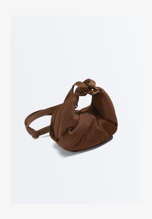 Miękka brązowa skórzana torebka na ramię z regulowanym paskiem z tkaniny i marszczonym, luźnym wzorem na jednolitym jasnym tle.