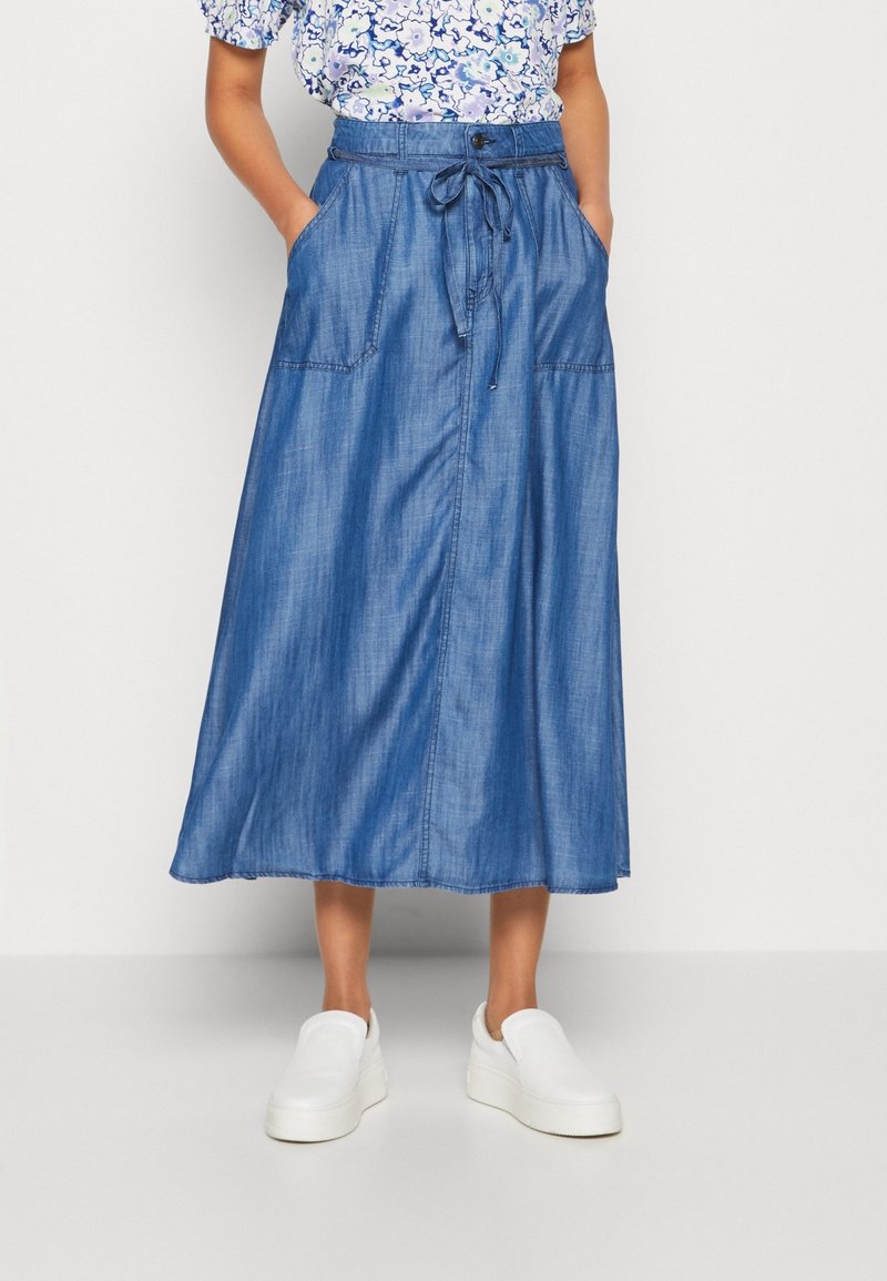 Denim maxikjol med dragsko i midjan, stora sidofickor och en mjuk textur. Färg är medelblå, med en rak silhuett.