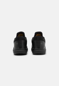Scarpe da ginnastica nere viste di spalle, con una tomaia in pelle e rete liscia, design minimalista e suole in gomma testurizzata.