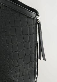 Sort håndtaske med en struktureret faux krokodillefinish, skarpe kanter og sølv lynlåsdetalje med en matchende læder trækklap.