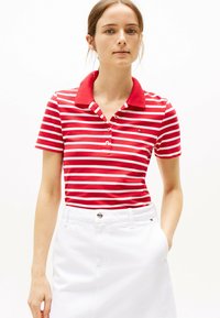 Rood-wit gestreepte poloshirt met een effen rode kraag en drie knopen, gecombineerd met een witte rok. Zachte stoftextuur.