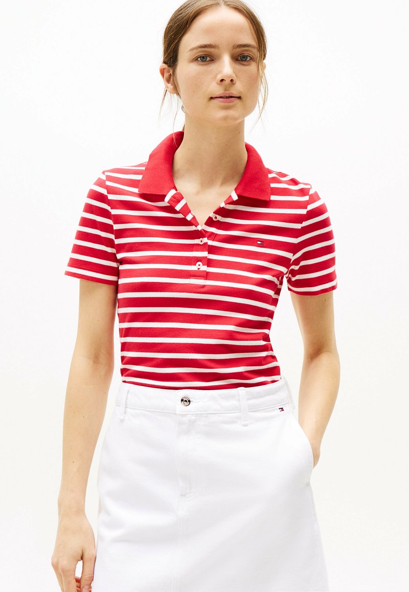 Rood-wit gestreepte poloshirt met een effen rode kraag en drie knopen, gecombineerd met een witte rok. Zachte stoftextuur.