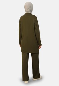 Long-sleeve, olive green outfit with a textured, loose-fit top and matching pants. The back view shows a rounded hem and simple design.